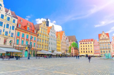 Polonya 'nın Wroclaw kentinin eski şehir merkezindeki Rynek Pazar Meydanı' nda renkli sanat cepheleri ve yürüyen insanlarla dolu renkli geleneksel binalar dizisi.