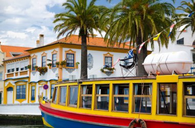 Yazın Portekiz Aveiro, Portekiz 'in küçük Venedik' i, Vouga Nehri, Portekiz 'in Aveiro Chanel' i, tipik turist teknesi, palmiye ağaçlarından oluşan arka planda renkli tekne, camları boyalı beyaz klasik evler.