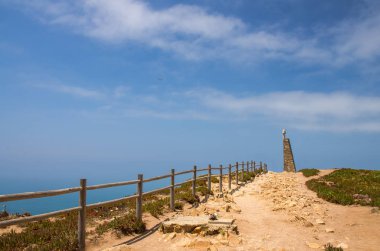 Portekiz, Cabo da Roca, Avrupa 'nın Batı Cape Roca' sı, Cape Roca 'da yürüyüş yolları, taş yolda ahşap korkuluklar, Cabo da Roca' daki anıtın tepesinde bir haç.