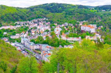 Karlovy Vary 'nin (Carlsbad) en iyi panoramik manzarası renkli güzel binalar, Tepla nehri ve yeşil ağaçlı Slavkov Ormanı tepeleri, Batı Bohemya, Çek Cumhuriyeti