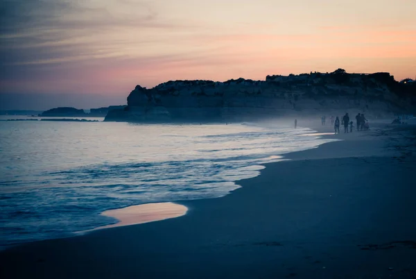 葡萄牙 阿尔加维 波蒂毛岛上最好的海滩 普拉亚达罗沙 在大西洋波涛上黄昏的淡紫色金色天空 一个男人和他的狗在海滩上玩耍 城市的黄昏全景 — 图库照片
