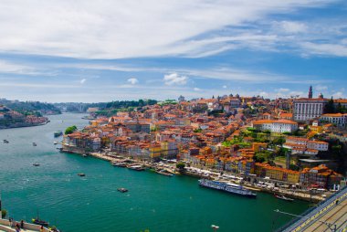Portekiz, Douro nehri, Porto 'nun harika panoramik manzarası, Porto' nun turistik merkezi, Porto 'da güneşli bir gün, Porto' nun üzerinde açık beyaz bulutlar, Porto 'da kırmızı çatıları olan renkli evler.