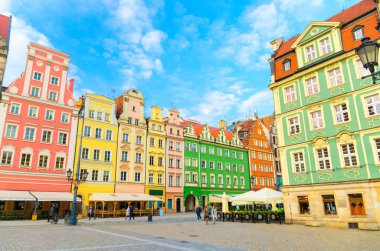 Renkli ön cepheleri ve kaldırım taşı üzerinde sokak lambası olan renkli geleneksel binalar dizisi eski kasaba tarihi şehir merkezi Wroclaw 'da Rynek Pazar Meydanı, mavi gökyüzü arka planı, Polonya
