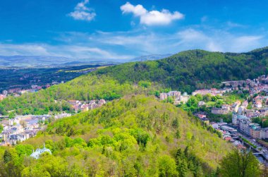 Karlovy Vary 'nin (Carlsbad) en iyi panoramik manzarası renkli güzel binalar, Tepla nehri ve yeşil ağaçlı Slavkov Ormanı tepeleri, Batı Bohemya, Çek Cumhuriyeti