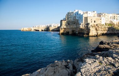 Güney İtalya 'nın Puglia Apulia bölgesinde, Polignano kasabasındaki mağaralar ve kayalıklardaki beyaz binalar.