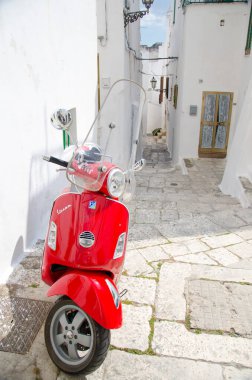 Ostuni, Italia - 23 Nisan 2017: Güney İtalya 'nın Puglia Apulia bölgesinde beyaz binaları olan Ostuni kasabasının dar sokaklarında kırmızı Vespa scooter' ı