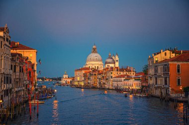 Büyük Kanal su yolu olan Venedik şehri. Grand Canal boyunca gece ışıkları olan binalar. Alacakaranlıkta Punta della Dogana 'daki Santa Maria della selam Roma Katolik kilisesi. Venedik Bölgesi, İtalya.