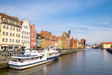Gdansk, Polonya, 15 Nisan 2018: Motlawa nehir suyundaki beyaz turist teknesi, tipik renkli evler binalar ve tarihi kent merkezinde yer alan Long Bridge set gezinti caddesindeki Zuraw Crane