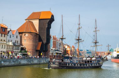 Gdansk, Polonya, 15 Nisan 2018: Motlawa nehir suyu üzerinde ortaçağ ahşap gemisi, tipik renkli evler binalar ve tarihi kent limanındaki Long Bridge seti gezinme güvertesi caddesinde Zuraw Crane
