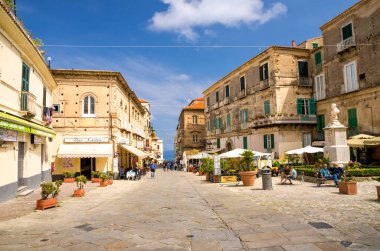 Tropea, İtalya - 9 Mayıs 2018: Kafeleri ve restoranları olan şehir sokakları, balkonları ve pencereleri olan binalar, arkasında bulutlar olan mavi gökyüzü, Calabria