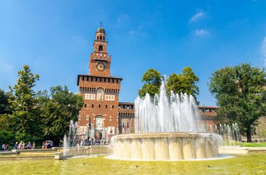 Milan, İtalya, 9 Eylül 2018: Eski ortaçağ Sforza Kalesi Castello Sforzesco cephesi, duvarlar ve kule La torre del Filarete, ağaçlar, güzel bir yaz günü çeşme, açık mavi gökyüzü, Lombardiya