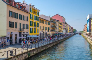 Milan, İtalya, 9 Eylül 2018: İnsanlar setin üzerinde yürüyor, Naviglio Grande büyük kanal su yolu ve yaz günü mavi gökyüzü arka planına sahip tipik renkli binalar üzerinde.
