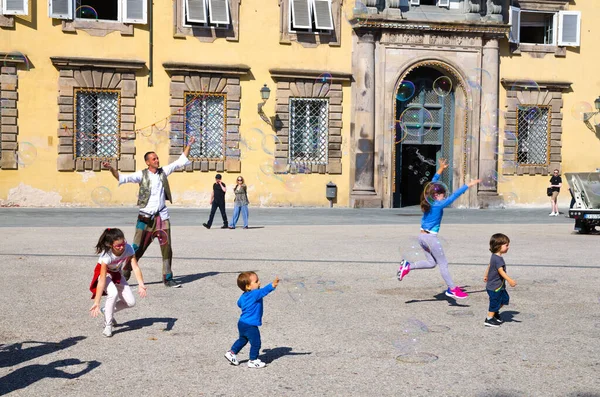 Lucca, Italia, 14 de septiembre de 2018: el hombre está soplando burbujas de jabón de colores y jugando con niños pequeños — Foto de Stock