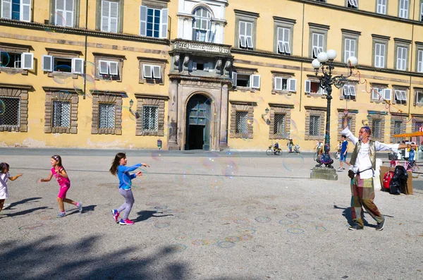 Lucca, Italia, 14 de septiembre de 2018: el hombre está soplando burbujas de jabón de colores y jugando con niños pequeños — Foto de Stock