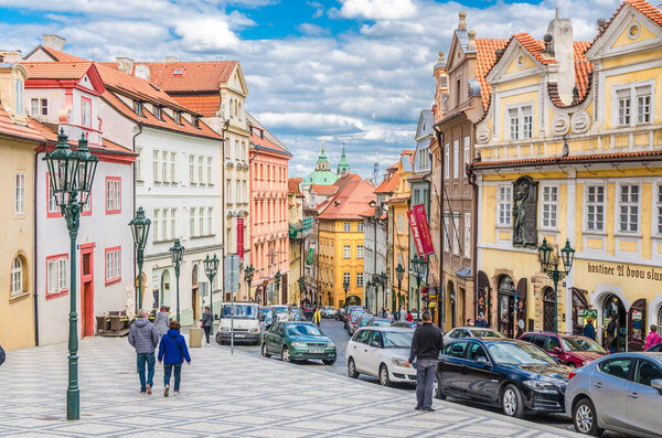 Prague, Czech Republic, May 13, 2019: people tourists are walking down cobblestone street in old historical city centre Lesser Town Mala Strana district with colorful buildings, Bohemia