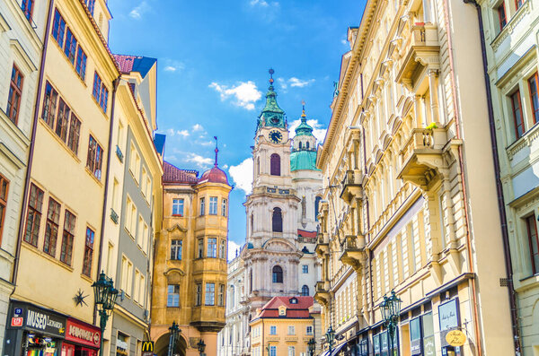Prague, Czech Republic, May 13, 2019: The Church of Saint Nicholas is Baroque catholic church in the Lesser Town Mala Strana district, narrow street of city, blue sky white clouds background, Bohemia
