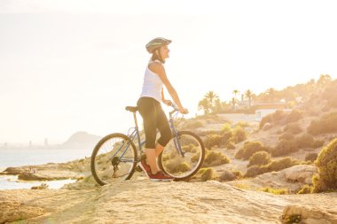  Plajda bisiklet süren bir kadın.
