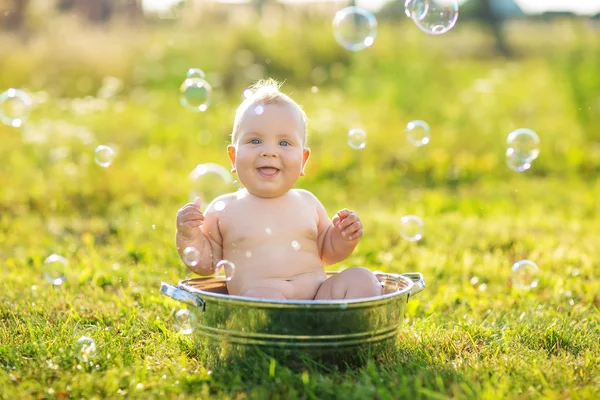 Счастливый ребенок купается летом в миске — стоковое фото
