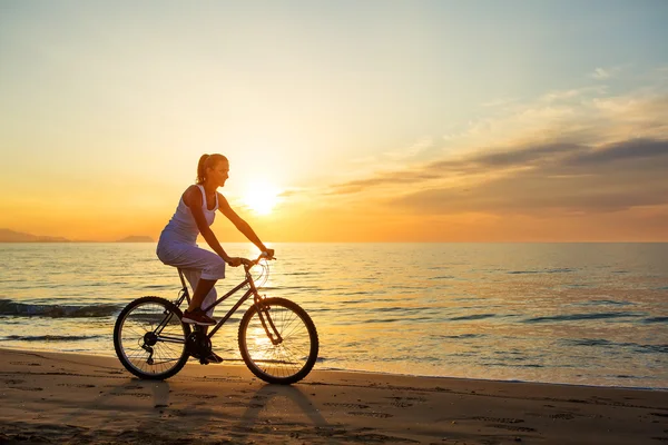 Frau im Urlaub radelt am Strand — Stockfoto