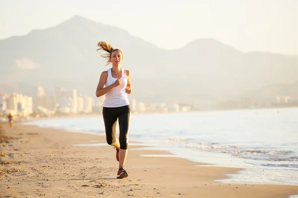 Kaukasisk kvinna jogging på havsstranden — Stockfoto