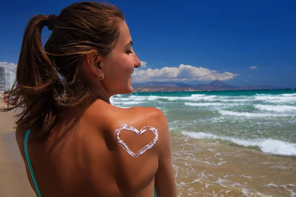 Een hart van de crème op de vrouwelijke rug op het strand — Stockfoto