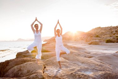 İki kız kardeş Mediterr sahil, yoga egzersizleri yapıyoruz