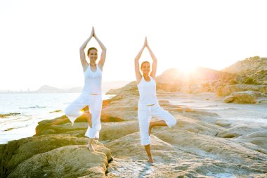 İki kız kardeş Mediterr sahil, yoga egzersizleri yapıyoruz