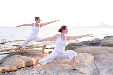 İki kız kardeş Mediterr sahil, yoga egzersizleri yapıyoruz
