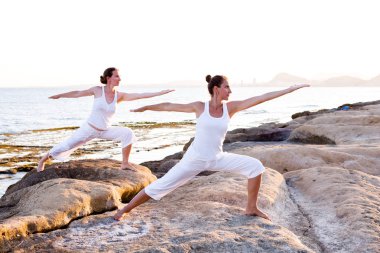 İki kız kardeş Mediterr sahil, yoga egzersizleri yapıyoruz