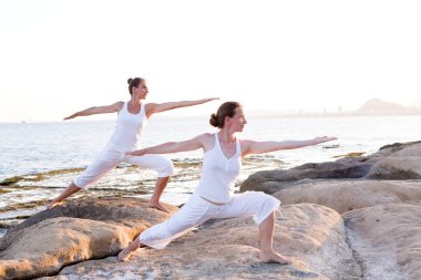 İki kız kardeş Mediterr sahil, yoga egzersizleri yapıyoruz