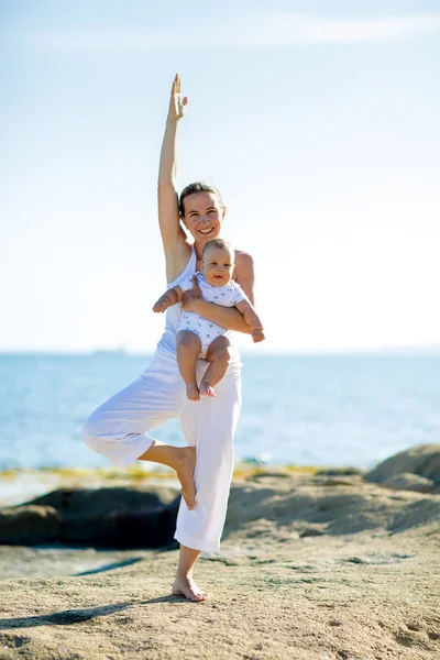 Une mère et un fils font des exercices de yoga au bord de la mer de M — Photo