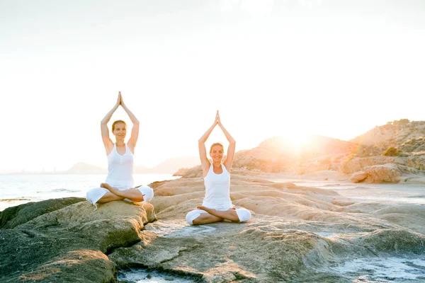Två systrar gör yogaövningar på havsstranden av Atmos. — Stockfoto