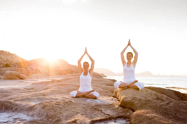 Två systrar gör yogaövningar på havsstranden av Atmos. — Stockfoto