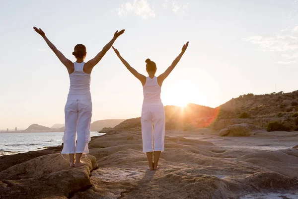 Dos hermanas están haciendo ejercicios de yoga en la orilla del mar de Mediterr — Foto de Stock