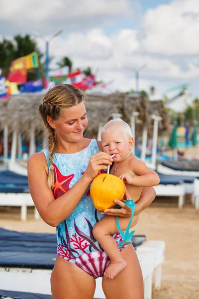 Matka i syn są pić kokosowe na plaży — Zdjęcie stockowe