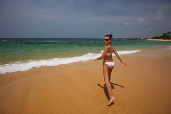 Een vrouw in witte bikini is plezier op de kust — Stockfoto