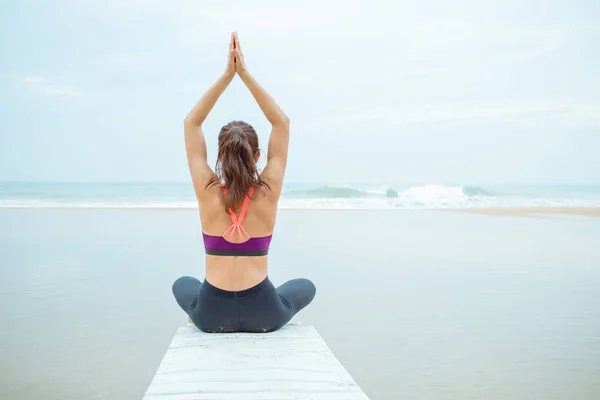 Kaukasische Frau praktiziert an einem bewölkten Tag Yoga am Strand — Stockfoto