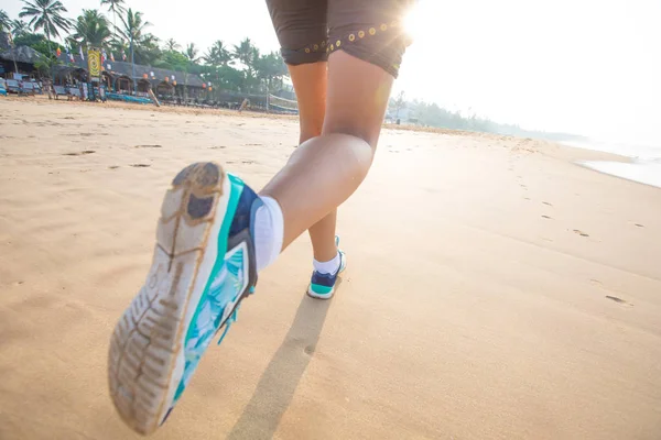 Fötter av kvinnan som jogging vid havet på sunrise — Stockfoto