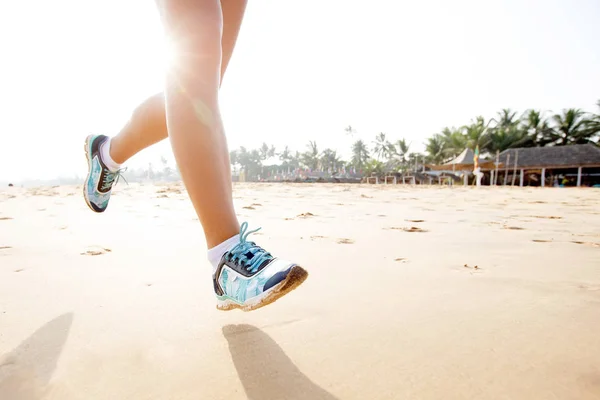 Fötter av kvinnan som jogging vid havet på sunrise — Stockfoto