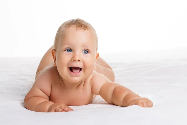 Lindo bebé sonriente acostado sobre una toalla aislada en blanco — Foto de Stock