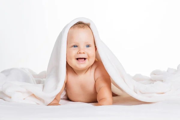 Bonito bebê sorridente sob toalha após o banho — Fotografia de Stock