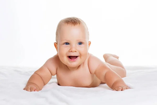 Симпатичный улыбающийся ребенок, лежащий на игрушке, изолированный на белом — стоковое фото