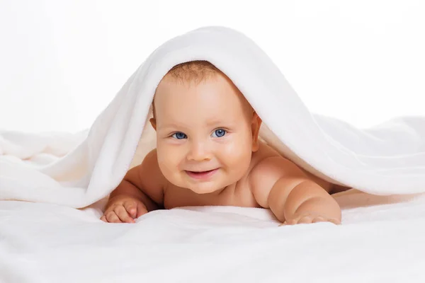 Bonito bebê sorridente sob toalha após o banho — Fotografia de Stock
