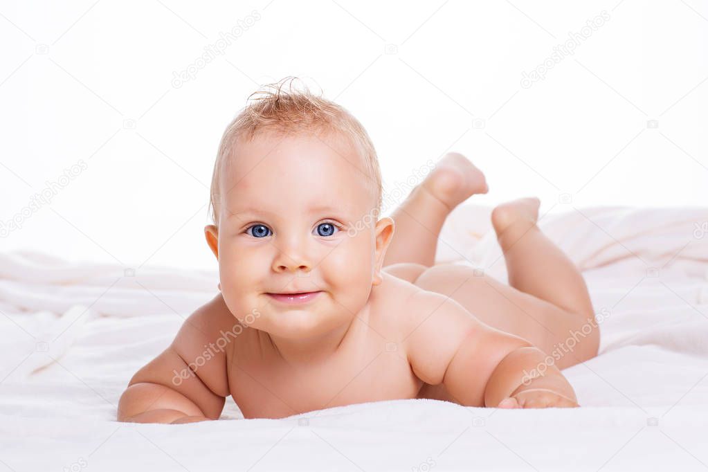 Cute smiling baby lying on towel isolated on white