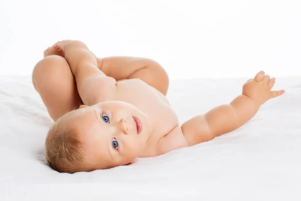 Lindo bebé sonriente acostado sobre una toalla aislada en blanco — Foto de Stock