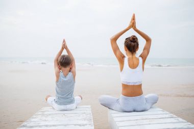 Bir anne ve bir oğlu deniz kıyısı t, yoga egzersizleri yapıyoruz