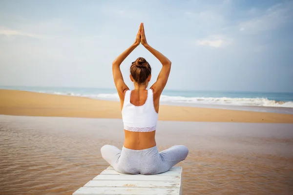 Kaukasische Frau praktiziert Yoga an der Küste des tropischen Ozeans — Stockfoto