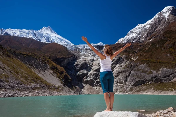 Mujer está haciendo ejercicios de yoga cerca de un gran lago en el circo de Manaslu — Foto de Stock