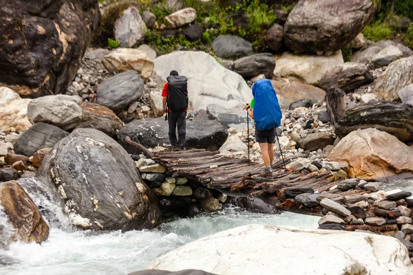 Hikers are crossing wooden bridge in highlands of Himalayas on M — Stock Photo, Image