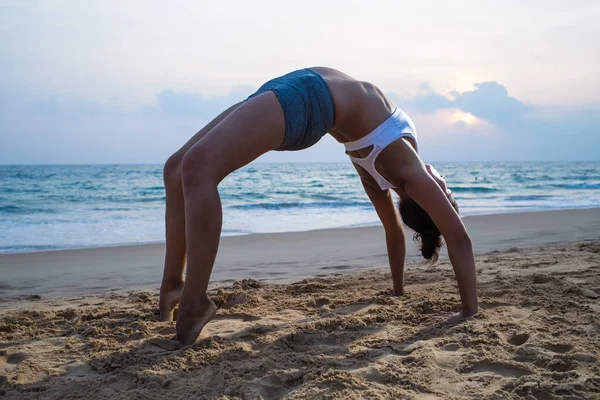 Mujer embarazada de aspecto natural practicando yoga en la orilla del mar a — Foto de Stock